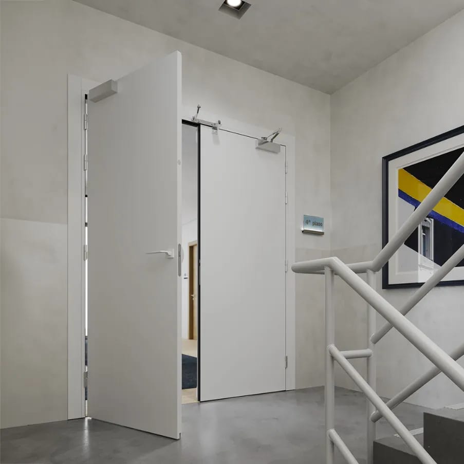 Porta tagliafuoco bianca con chiudiporta installata sul vano scala di un condominio