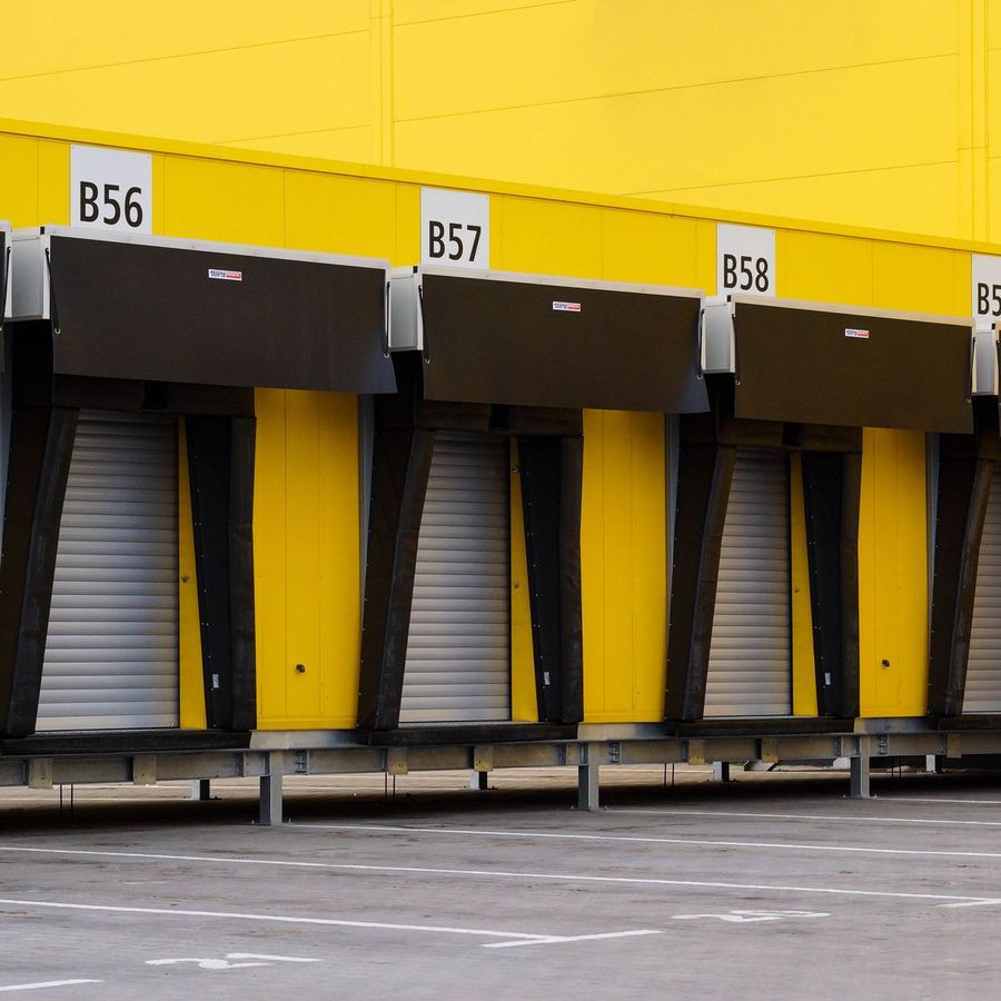 Fila di baie di carico numerate su un magazzino logistico con pareti gialle