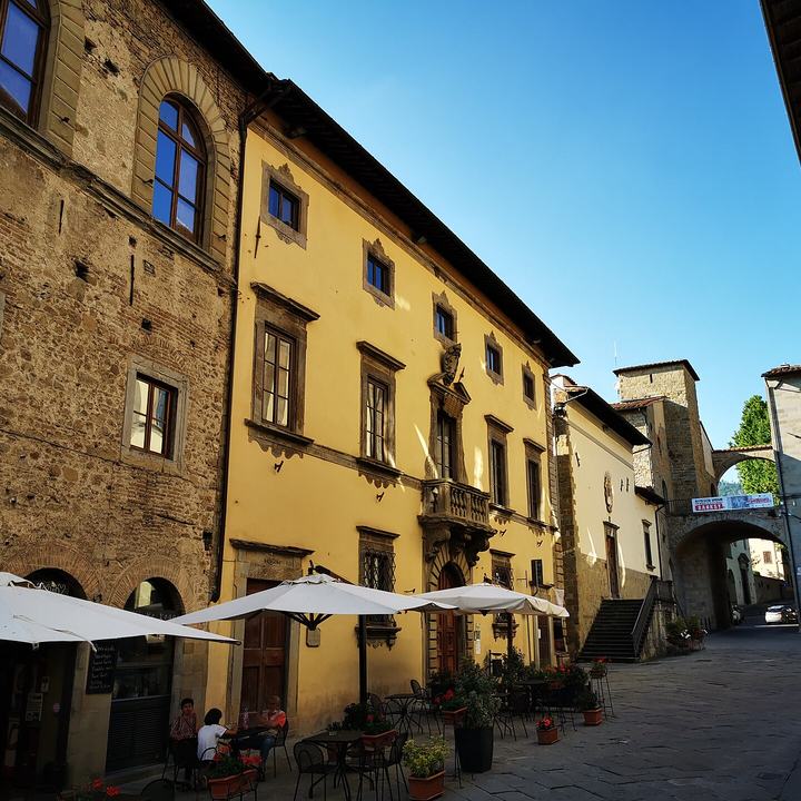 Piazza nel centro storico di Sansepolcro con un palazzo d'epoca e i tavolini di un bar